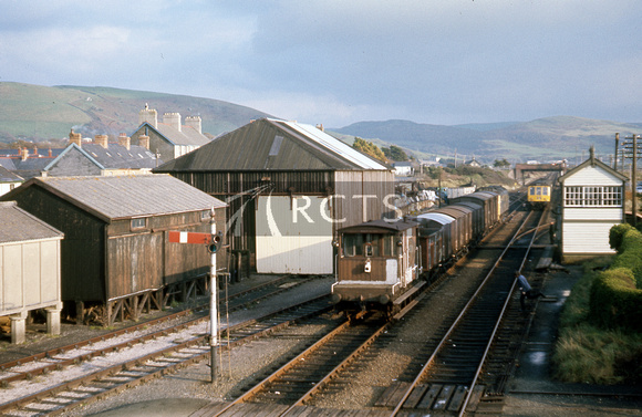LAN0299C - Tywyn (BR) yard and signal box viewed from an overbridge and showing goods train and DMU passing c October 1974